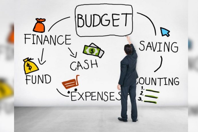 Businessperson in a suit sketches a budget mind map on a white wall, with Finance, Savings, Cash, and Expenses.