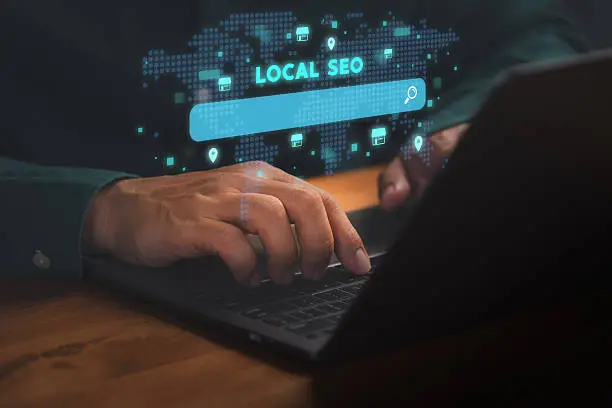 Person typing on a laptop with a glowing local SEO search bar and world map icons in the background.