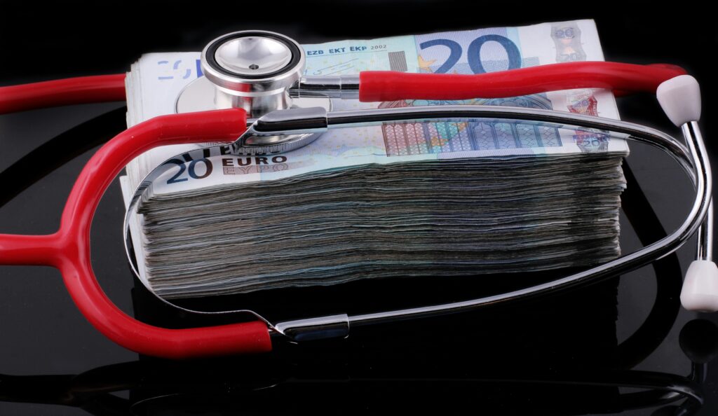 Stethoscope resting atop a thick stack of 20 euro banknotes, suggesting medical costs in healthcare.